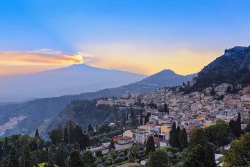 Fototapeta na wymiar View of the city of Taormina and the active volcano Etna at suns