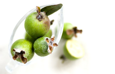 green fruits - feijoa on a white background in a transparent container