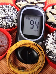 Glucometer, muffins in red cups and tape measure