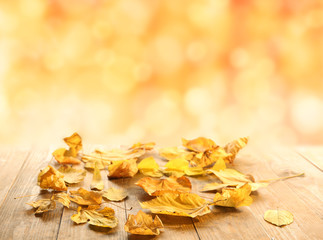 Yellow autumn leaves on wooden table, on nature background