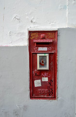 Antique red metallic mailbox outside a building facade