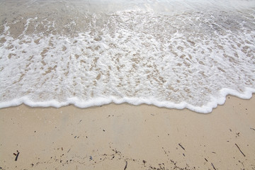 Fototapeta na wymiar Foamy wave on sandy beach