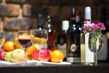 Catering service with two glasses red and white wine, fruits and alcohol buttles on bartender background