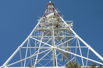 Tower of communication antenna with blue sky background, view from the bottom