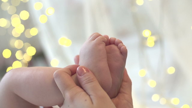 mother holding newborn baby feet on the background bokeh lights