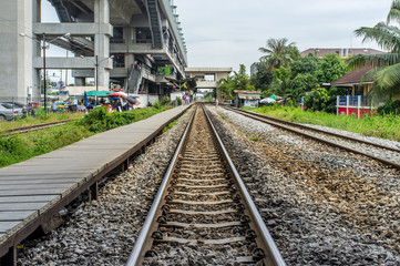 Fototapeta na wymiar Railway tracks to horizon with train station building and sky background