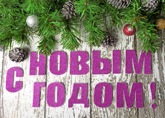 The inscription in Russian "happy new year" with fir branches on white wooden wall