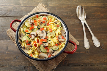 vista dall'alto Pasta italiana con funghi zucchini e pomodoro su sfondo legno rustico