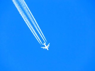 Airplane with chemtrails on blue sky