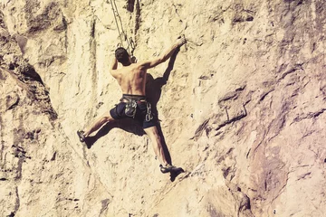 Fototapeten Man climbing a mountain wall. © daviles