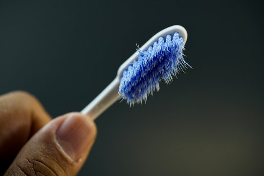 Worn Out Toothbrush Held In Hand