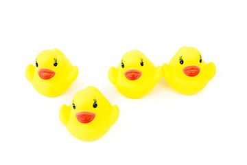 Four yellow rubber ducks in a line, one in front of the line, isolated on white background, available copy paste