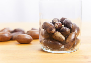 Acorns on glass jar over wooden surface