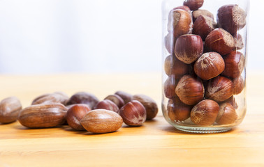 Pecan walnuts and hazelnut on glass jar over wooden surface