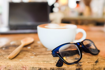 Glasses with laptop and coffee cup on wood table