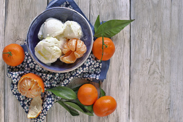 Ice cream  in bowl with mandarins on wooden background 