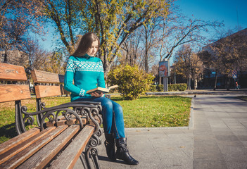 Девочка-подросток читает увлекательную книгу в осеннем парке