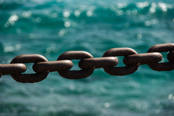 Rusty boat anchor chain in front of ocean