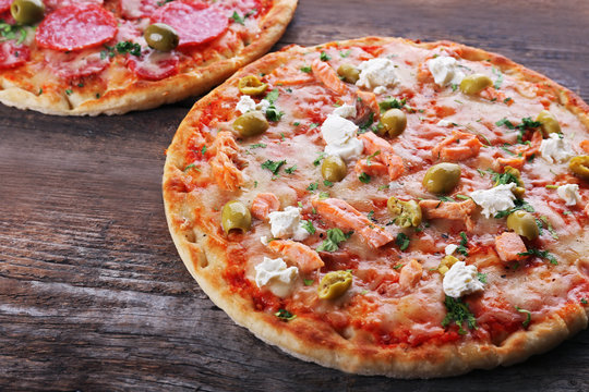 Two delicious tasty pizzas on wooden background
