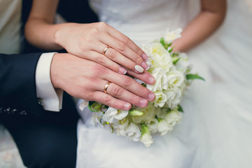 Obraz na płótnie Canvas the hands of bride and groom holding wedding bouquet close up