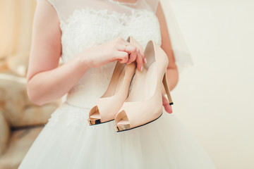 Bride holding beige wedding shoes