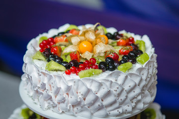 White tiered cake with chunks of berries and fruits