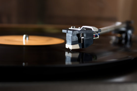 Record player stylus on a rotating disc with orange label