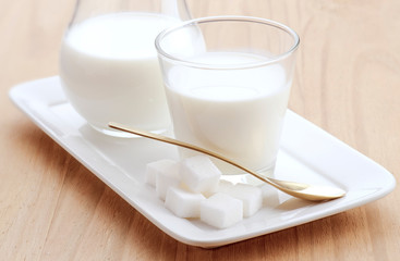 glass of milk with golden spoon and sugar cubes