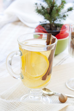 Fresh hot green tea in glass cup with lemon and cinnamon, chocolate cakes in basket and nuts and cinnamon in glass goblet.
