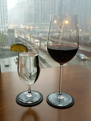 Wine glass and water glass on table looking out city window