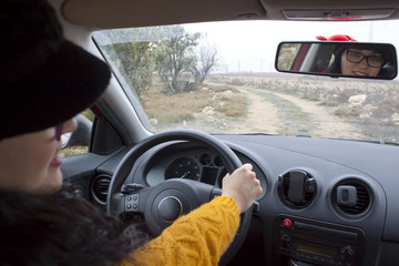 woman looking in the rear mirror of her car