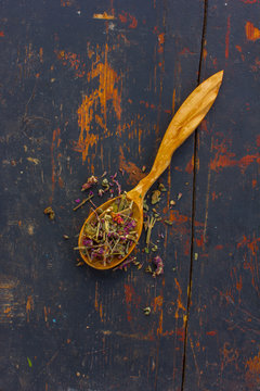 Dried herbs Salvia officinalis in a wooden spoon on the old cracked black board. Ingredient for cooking healthful beverage. The concept of herbal therapy. Ingredient for cooking healthful beverage