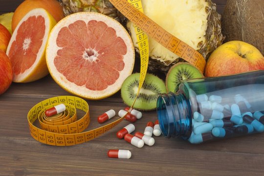 Dietary supplements for weight loss. Red grapefruit and fruit for weight loss. Fresh dietary food for athletes. Fruit on a wooden table.Balanced diet. Assortment of exotic fruits.
