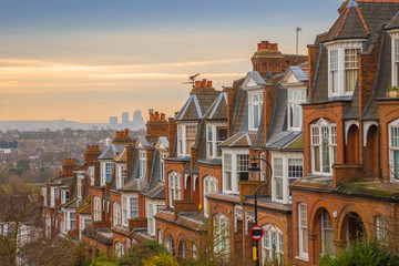 Typical British brick houses on a cloudy morning with sunrise and Canary Wharf at the background....