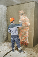 Plasterer spraying plaster on wall