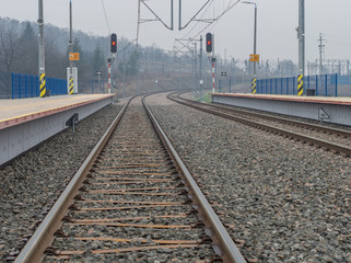 Train stop with double electrified railway track with railway signals and platforms