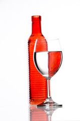 Red bottle and filled glass on white background