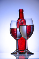 Red bottle and two filled stemware on a white background