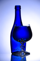 Blue bottle and wineglass on white background