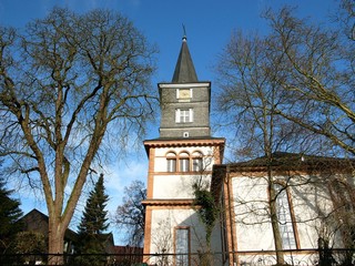 Kahle Bäume im Winter neben der evangelischen Kirche bei blauem Himmel und Sonnenschein in Wißmar...