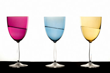 verre à pied de couleur  un rose, un bleu, un jaune, à moitié plein d'un liquide penché