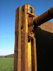 Rostiger Grabenverbau auf einem grünen Feld vor blauem Himmel im Sonnenschein an einer Baustelle...