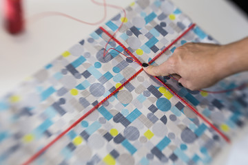White woman hand wrapping a colorful gift on a white table