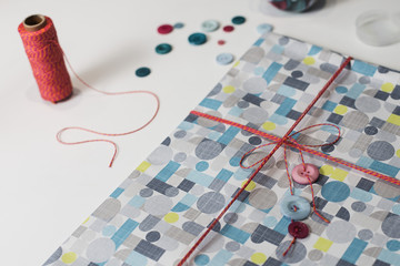 Gift present con colorful wrap paper and decoration buttons on a white table