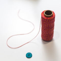 Red sewing thread on a white background