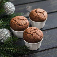 Chocolate muffins, Christmas tree and Christmas decorations on dark wooden surface
