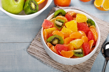 Closeup fruits salad in plate on blue wooden table