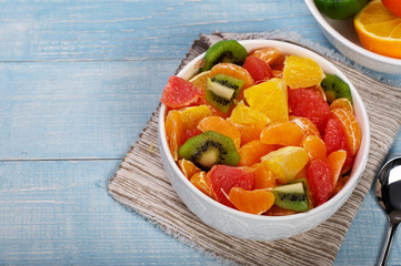 Closeup fruits salad in plate on blue wooden table