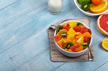 Fruits salad in plate on blue wooden table closeup