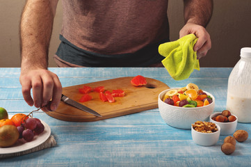 Man cooking at home preparing fruit salad